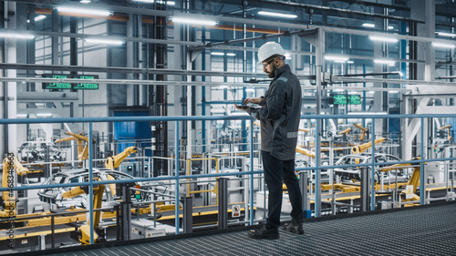 Obraz na plátně Car Factory Engineer in Work Uniform Using Laptop Computer