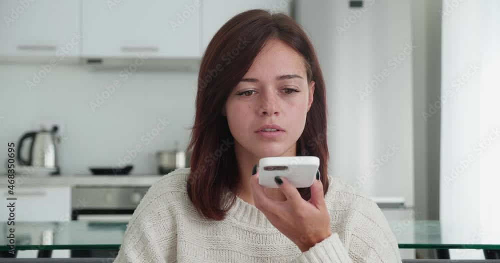 Close-up view of emotional woman recording a voice message on the phone sitting in cozy couch in modern room background. Close-up view of emotional woman recording a voice message on the phone sitting in cozy couch in modern room background.