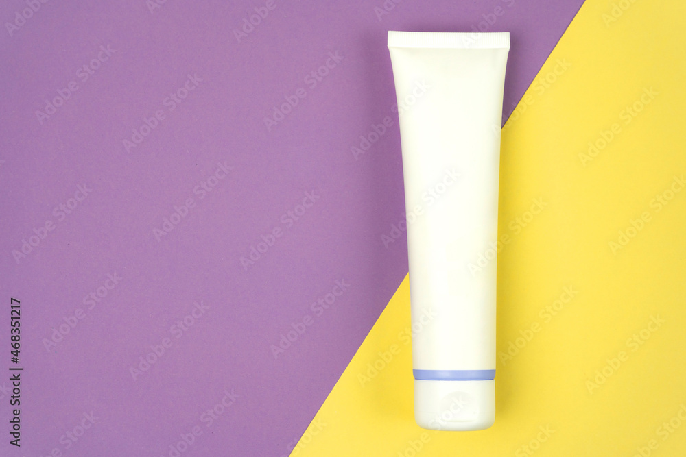 Hand cream, moisturizer, toothpaste, lotion jar plastic tube on lilac and yellow background. Brand spa packaging mock up. Copy space Hand cream, moisturizer, toothpaste, lotion jar plastic tube on lilac and yellow background. Brand spa packaging mock up. Copy space