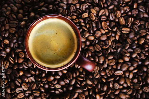 Coffee cup with free space for text on roasted coffee beans close up