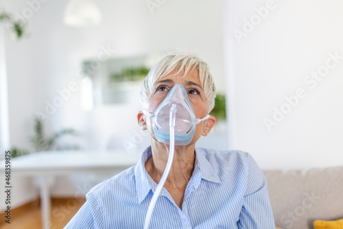Sick elderly woman making inhalation, medicine is the best medicine. Ill senior woman wearing an oxygen mask and undergoing treatment for covid-19. Senior woman with an inhaler photo