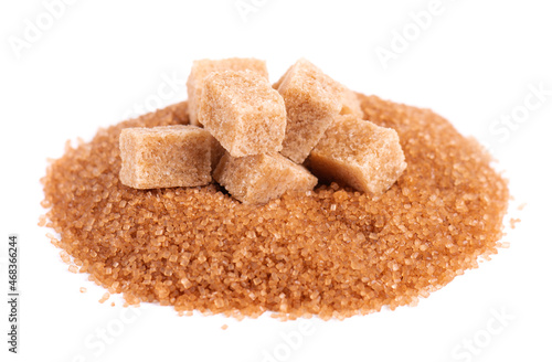 Brown sugar isolated on white background. Heap of cane sugar crystals and sugar cubes.