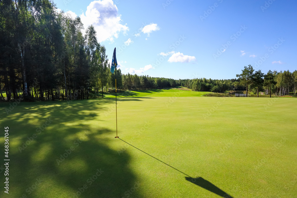 Obraz premium Flag shadow on the golf course with green grass. High quality photo