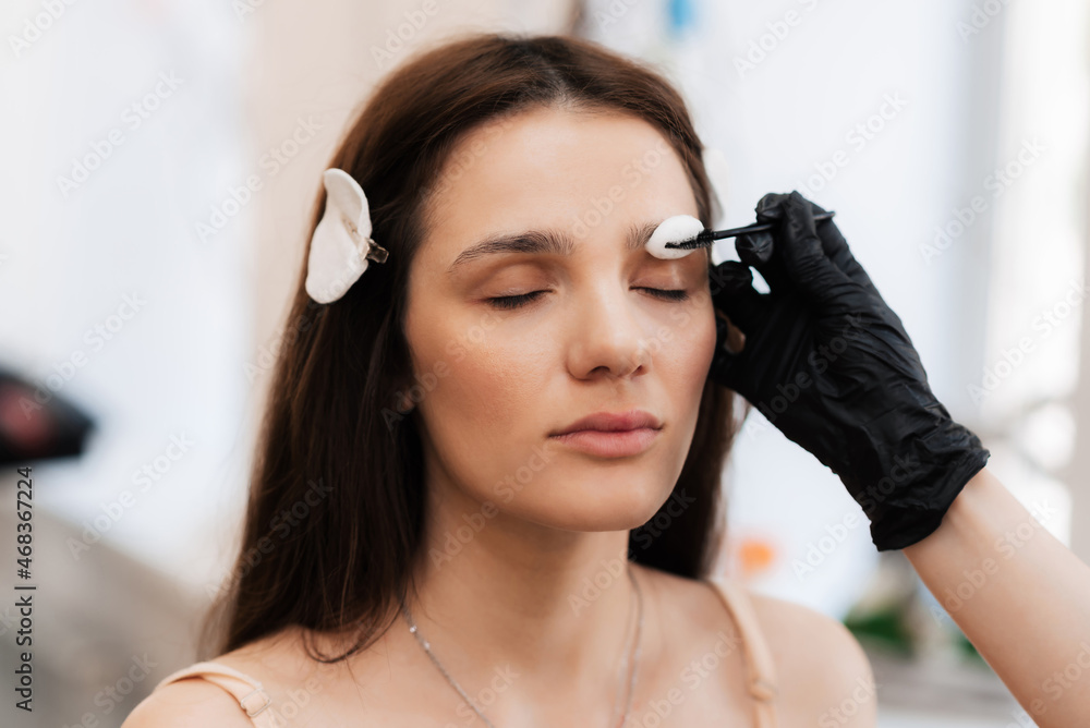 Fototapeta premium The cosmetologist-brovist begins the first stage, in the correction of eyebrows, with the cleansing of the skin in the beauty salon. Professional facial care