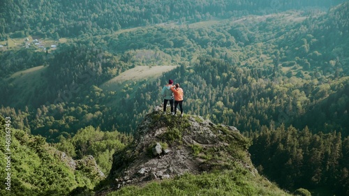 A young woman approaches a man to a cliff in a mountainous area. Travel