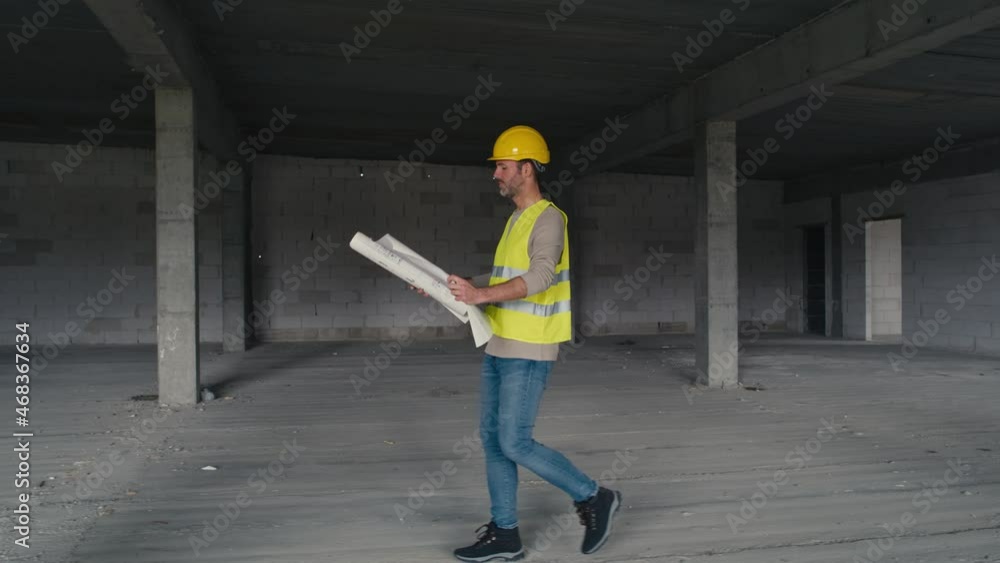 Wide image of caucasian engineer walking on construction site and browsing building plans. Shot with RED helium camera in 8K Wide image of caucasian engineer walking on construction site and browsing building plans. Shot with RED helium camera in 8K