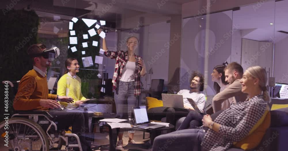 Disabled businessman in a wheelchair at work in modern open space coworking office on team meeting using virtual reality goggles and drone simulation. Effective teamwork in a startup business. Disabled businessman in a wheelchair at work in modern open space coworking office on team meeting using virtual reality goggles and drone simulation. Effective teamwork in a startup business.