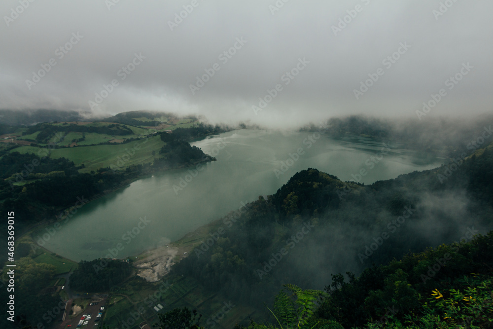Aerial view of the lake with forests and mountains on a cloudy and dark day