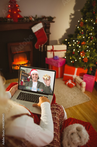 Santa claus making laptop christmas video call with smiling caucasian man in santa hat