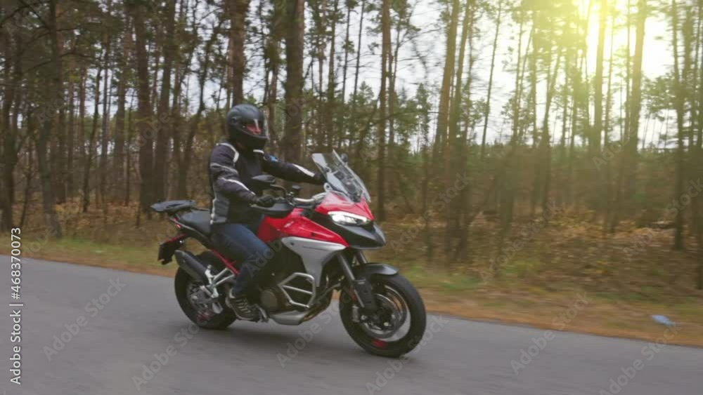 Man traveling country road on red motorcycle. Motorbike tour journey. Biker man driving his sport touring bike. Slow motion shot Man traveling country road on red motorcycle. Motorbike tour journey. Biker man driving his sport touring bike. Slow motion shot
