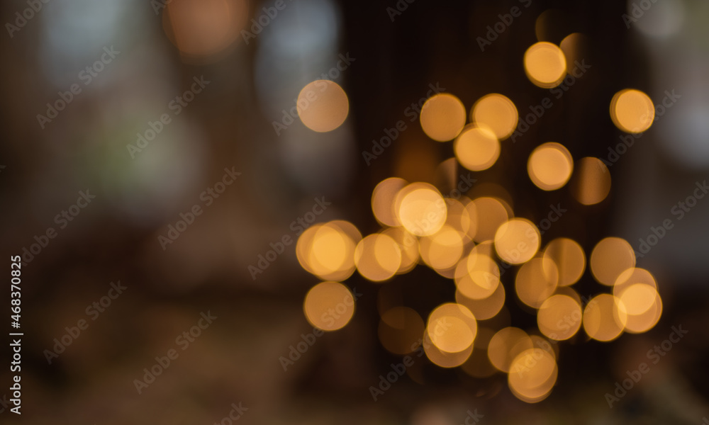 Obraz premium Abstract dark christmas background with blurred golden bokeh effekt and for special occasions.