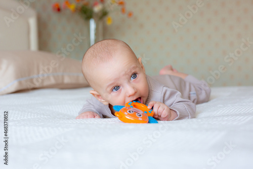 baby boy with a rattle on the bed