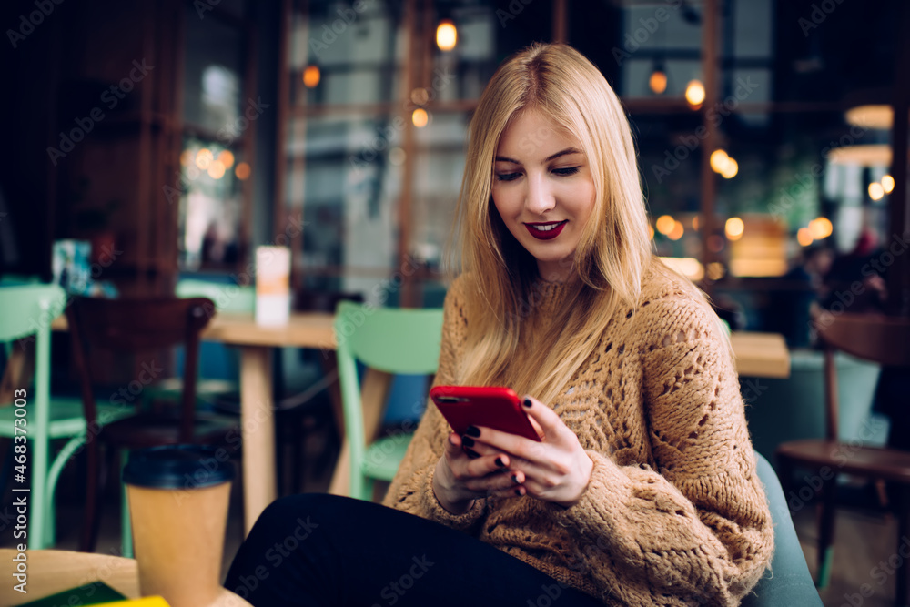 Cheerful young lady using smartphone in cafeteria Cheerful young lady using smartphone in cafeteria