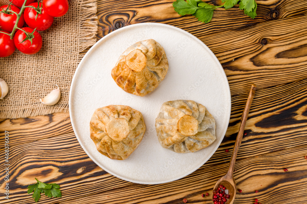 Fried Georgian khinkali on white plate on wooden table Fried Georgian khinkali on white plate on wooden table