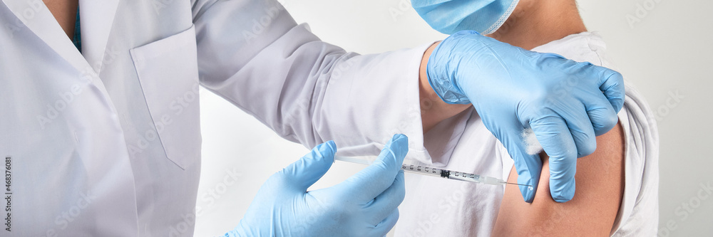 Fototapeta premium Close-up on hands in gloves with syringe and shoulder of the patient, teen kid. Covid 19, flu, tetanus or measles vaccine concept. Unrecognizable edic, doctor or nurse vaccinates school boy.