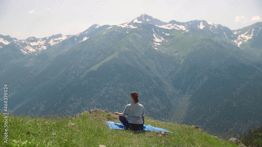 A young woman does yoga on the tops of mountains. Sports tourism