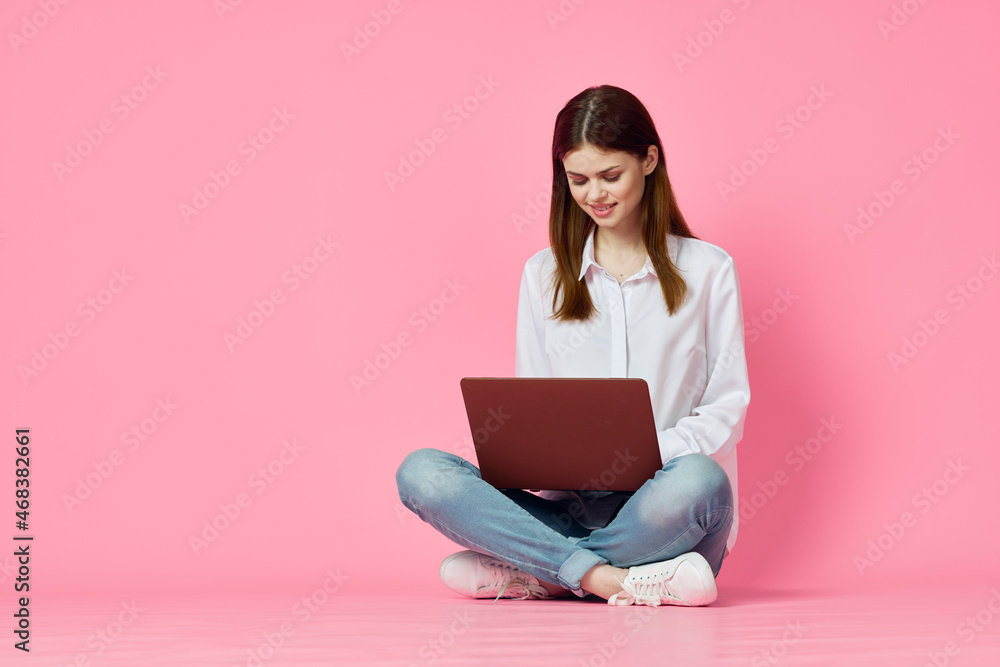 Naklejka premium woman with laptop sitting on the floor internet communication online pink background