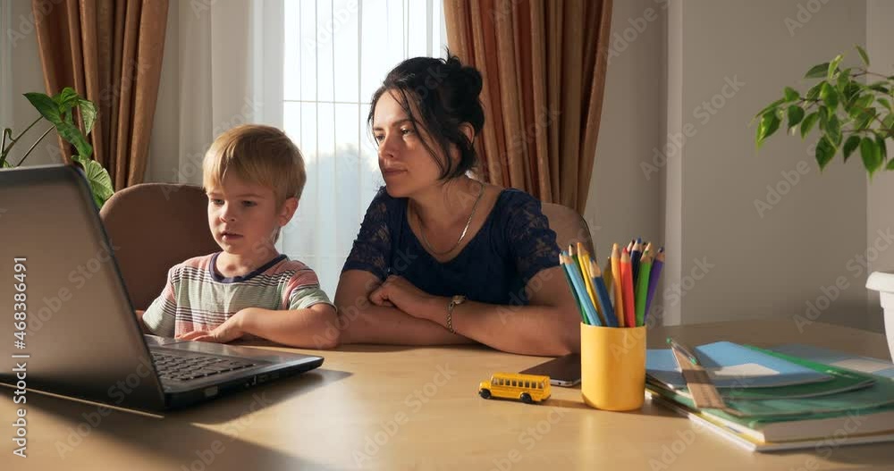 Mother Teach Child Study Online Using Laptop Computer. Little Boy Distance Learning at Home. Preschooler Kid Sits at Desk Table in Room Near Window 4K Mother Teach Child Study Online Using Laptop Computer. Little Boy Distance Learning at Home. Preschooler Kid Sits at Desk Table in Room Near Window 4K