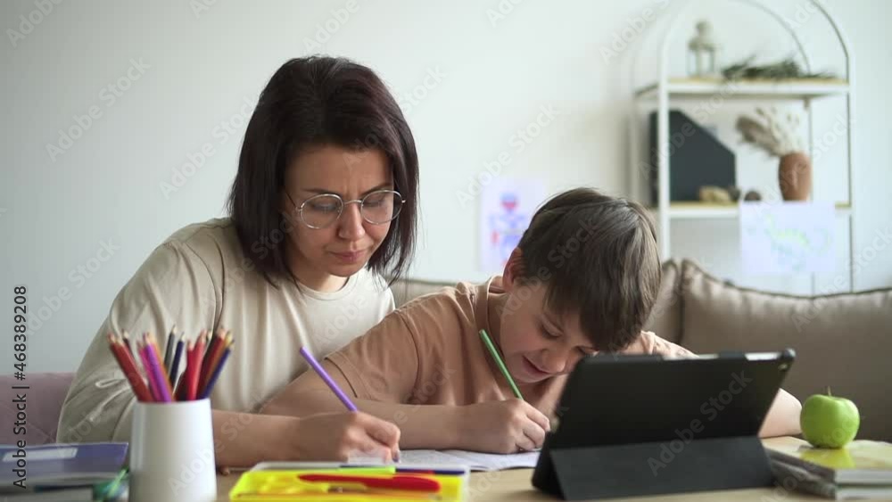 Mother and son learning at home together with tablet Spbd. Mom help boy with school homework, sit at desk with tablet computer, use pencil. Drawing with child for art task. Mother and son learning at home together with tablet Spbd. Mom help boy with school homework, sit at desk with tablet computer, use pencil. Drawing with child for art task.