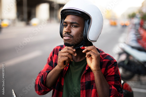 Handsome African man with scooter in the city. Young man riding a scooter.