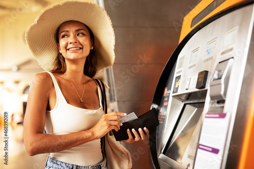 Happy smiling young woman withdrawing money from credit card. Young woman using ATM mashine.