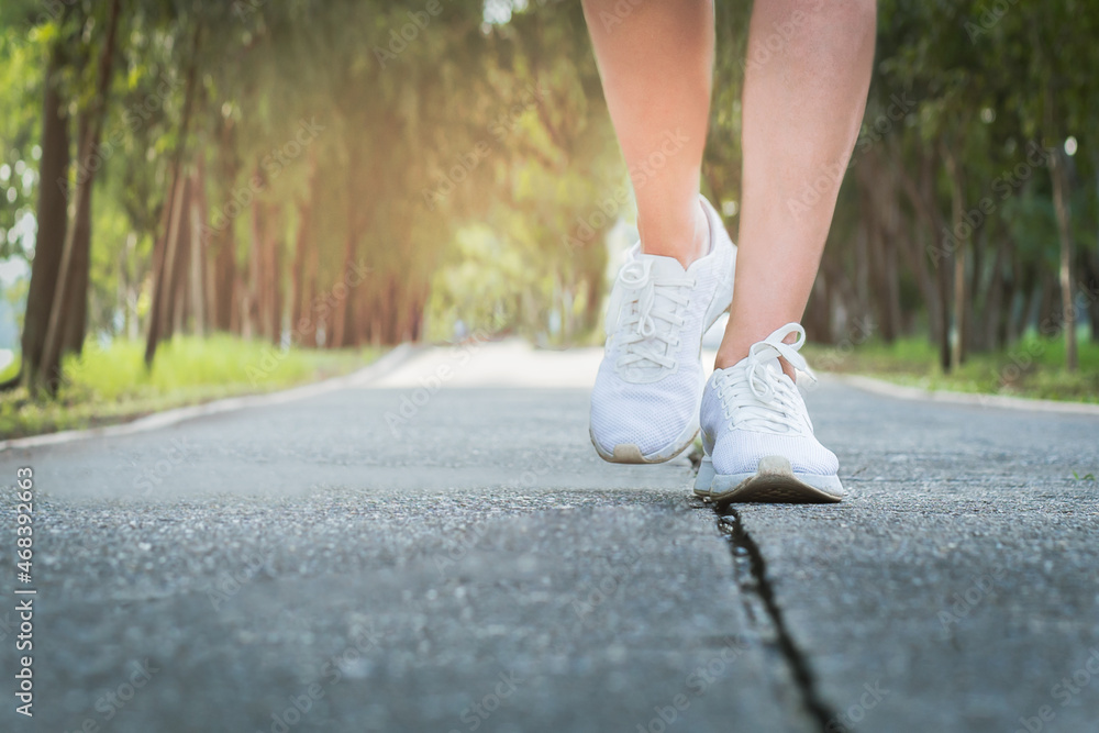 Female exercise walking on street in the park with close up on walking shoes. Female exercise walking on street in the park with close up on walking shoes.