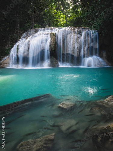 Scenic view of famous Erawan Waterfall breataking smooth flowing water stream with turquoise lagoon and fish swarm in lush rainforest. Kanchanaburi  Thailand. Long exposure.