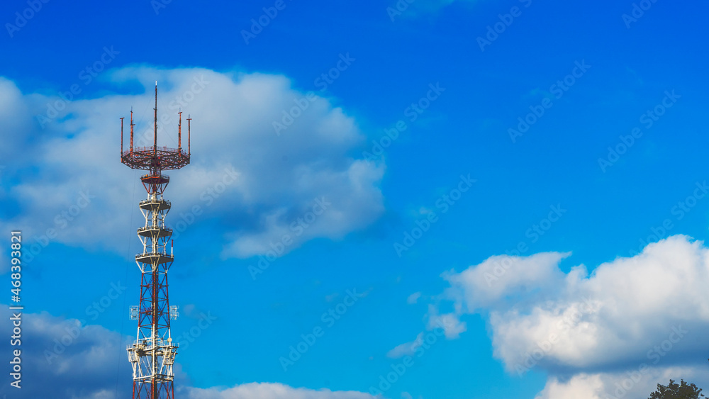 A TV tower on the background of a blue sky with clouds. History tellecommunication concept.