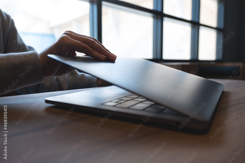 Closeup image of hands close and open a laptop computer on table after finished using it