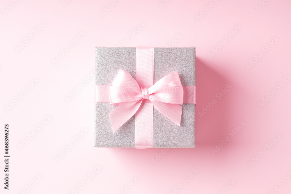 Silver glitter gift box with pink ribbon bow on pink background. Silver glitter gift box with pink ribbon bow on pink background.