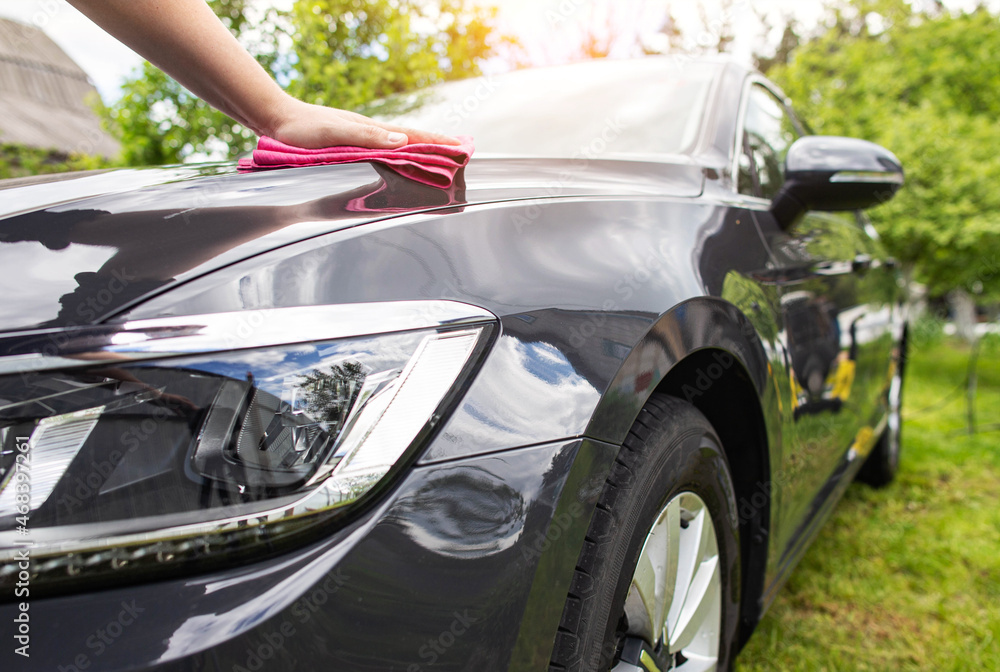 A man wipes his car with a towel after washing with car shampoo and polish. Car wash in nature A man wipes his car with a towel after washing with car shampoo and polish. Car wash in nature