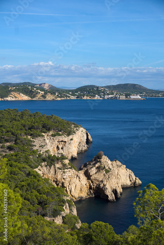 View on cliff through trees on Mallorca with blue water and town in background photo