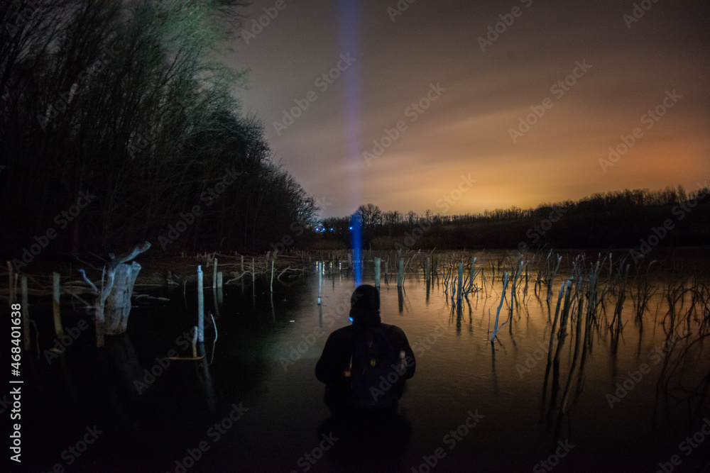 Obraz premium human on the lake forest in the night . Night landscape. Nightsky and clouds . Stars in the sky . Lights of the city . Evening forest . Landscapes of Ukraine . Night and morning time 