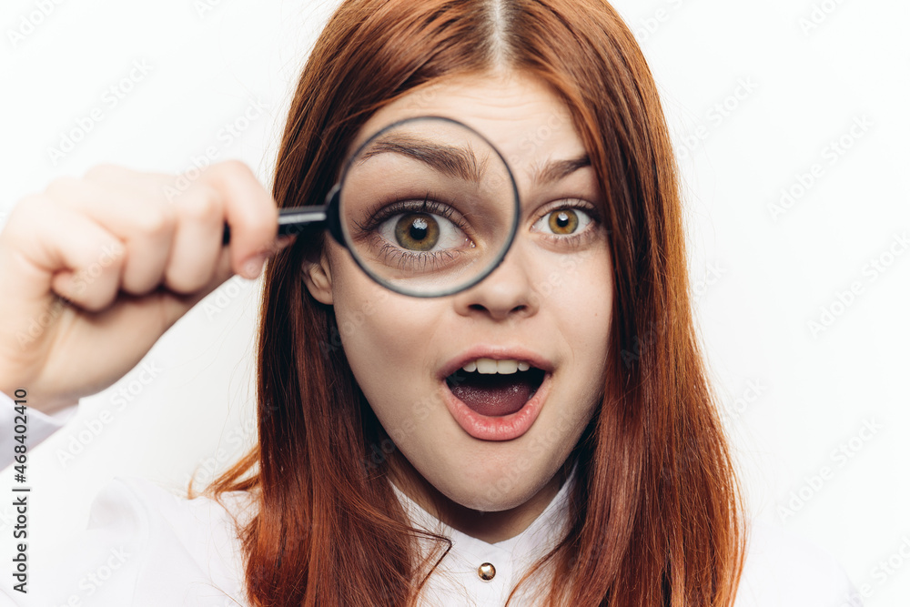red-haired woman in a white shirt with a magnifying glass in her hands searching red-haired woman in a white shirt with a magnifying glass in her hands searching