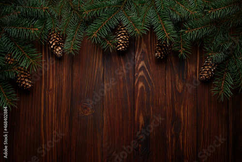 Christmas background with fir branches and cones on dark wooden board. Top view. Copy space. Xmas decoration