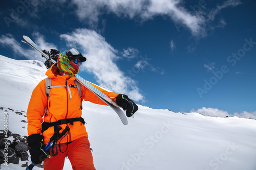 Wallpaper Mural Mountain portrait of a professional freeride skier in orange clothing with ski poles and skis on his shoulders. Stands high in the mountains on a snowy slope Torontodigital.ca