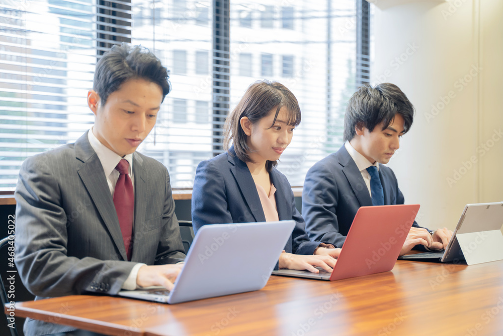 ノートパソコンで仕事をする３人の男女のビジネスマン