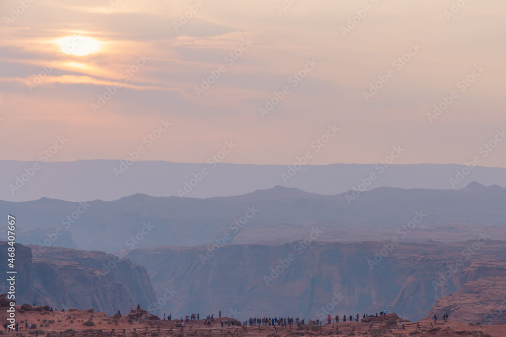 Obraz premium Scenic landscape. Sunset in desert with mountains, cloudy sky and silhouette of people enjoying the view