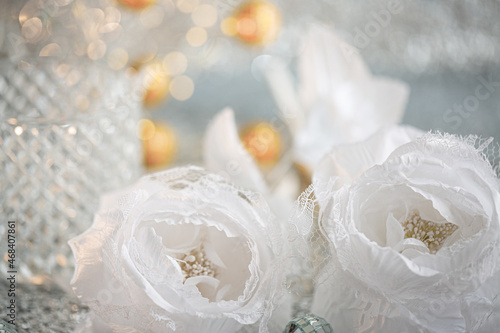 Silk white roses with lace and blurred light background with beautiful bokeh. Christmas decoration to decorate the festive table.