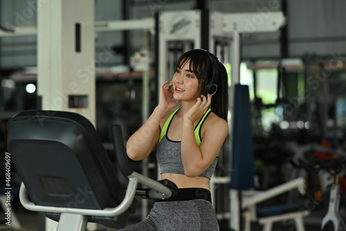Photo of a beautiful sporty girl listening to music while doing an exercise in the comfortable gym.