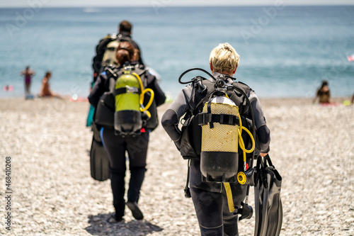 Three scuba divers with all equipment heading to the sea, Spain photo