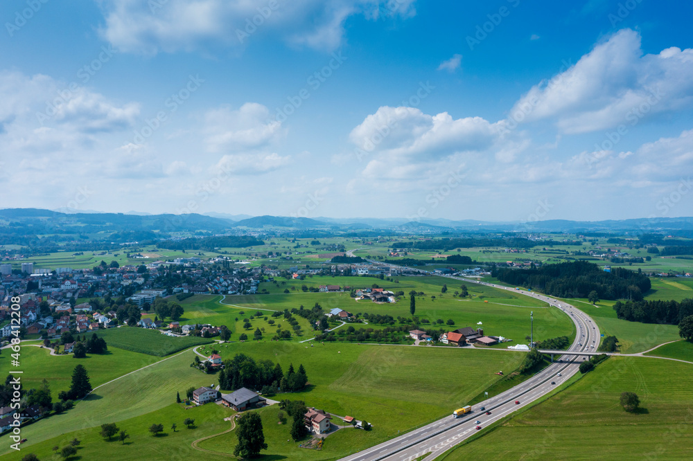 Obraz premium Panorama aerial view of the green Swiss hills on a summers day with blue skies.
