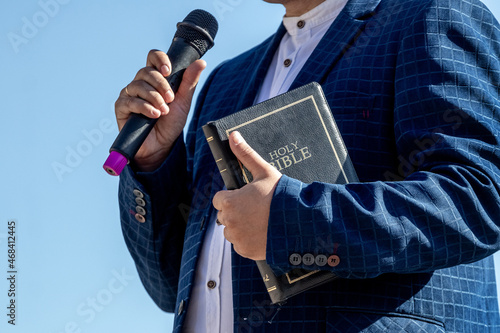 Pastor with a Bible in his hand during a sermon. The preacher delivers a speech photo