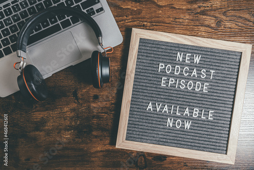 top view of letter board with text NEW PODCAST EPISODE on wooden table with laptop and headphones, podcasting concept photo