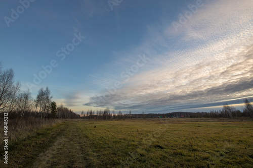 Landscape with delicate cirrus clouds over the field. Autumn field and sunset sky with clouds. Scenic evening landscape with blue sky, field and clouds.
