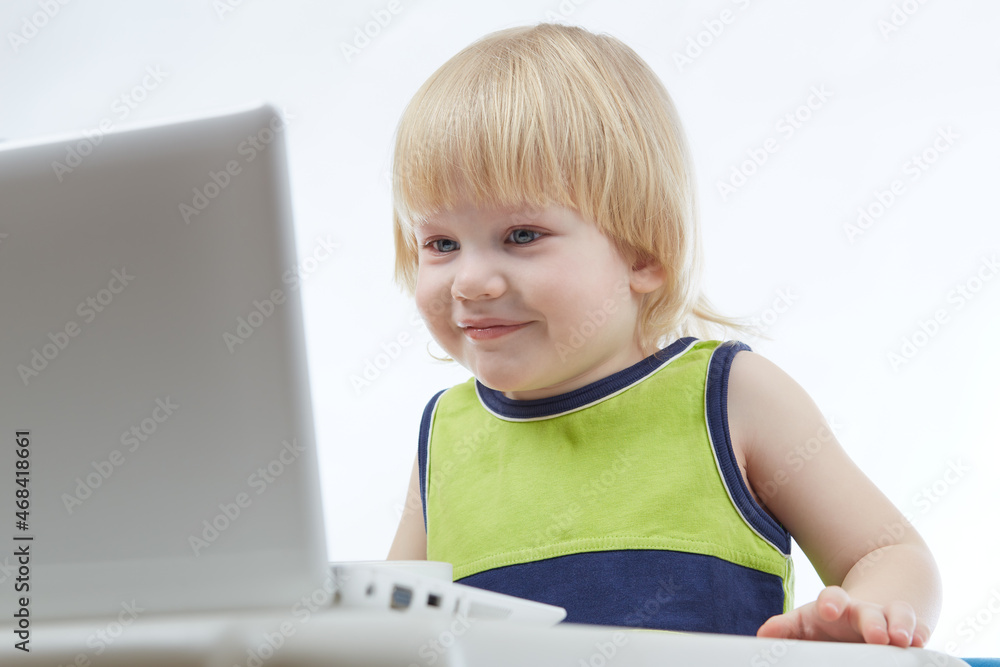Young blonde boy sitting at table with laptop. Online education concept Young blonde boy sitting at table with laptop. Online education concept