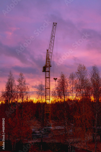 Construction crane on the background of the twilight sky at the construction site in autumn