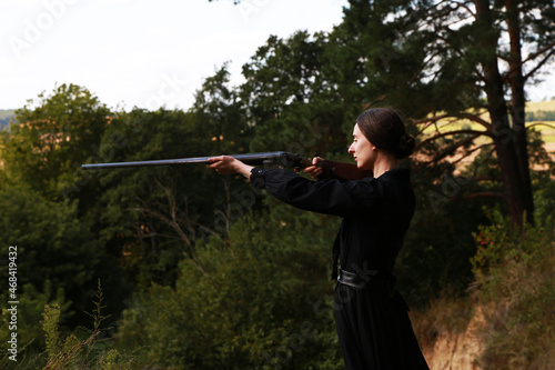 Woman with vintage shotgun in the forest