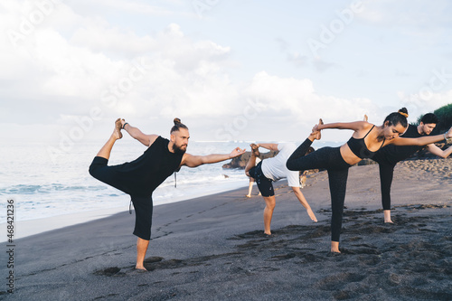 Man and woman enjoying yoga during morning sea breathing for training body shape in balance asana, inspired multiracial people keeping mental and physical strength during yoga concentration