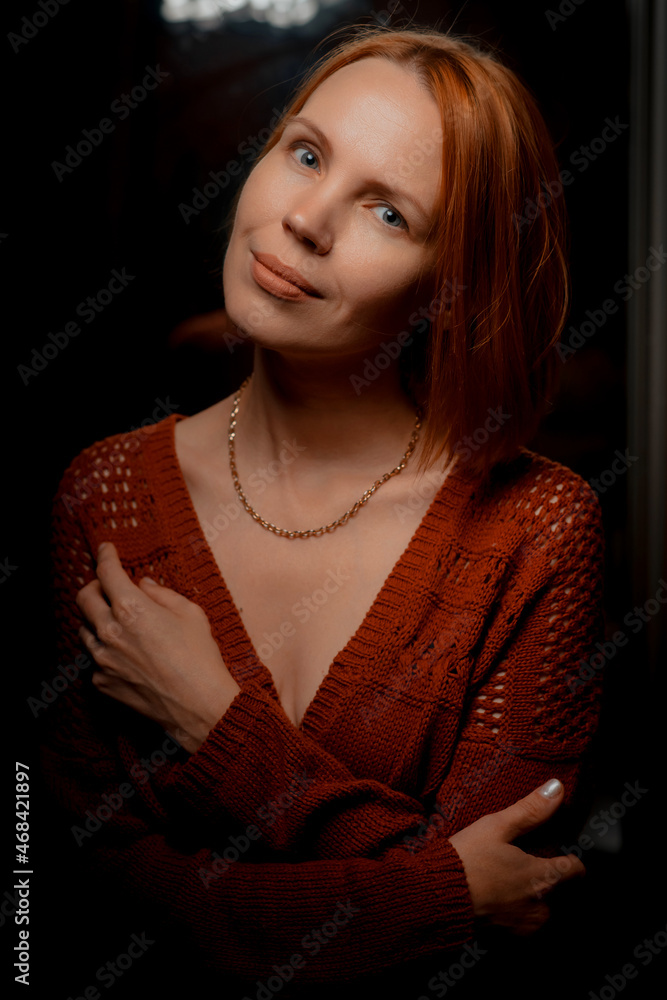 Attractive woman in her forties looking at the camera at home against a dark background. Attractive woman in her forties looking at the camera at home against a dark background.